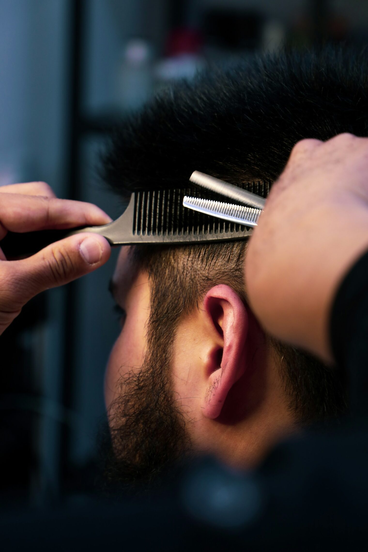 Barber knipt met effileerschaar en kam